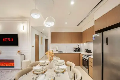 a kitchen with a table with chairs and a fireplace at Stunning 2BR Burj Khalifa View from Infinity Pool Grande Signature Residences in Dubai