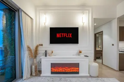 a living room with a fireplace with a tv above it at Stunning 2BR Burj Khalifa View from Infinity Pool Grande Signature Residences in Dubai