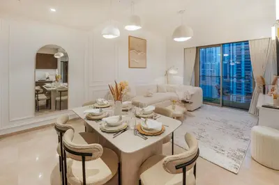 a white living room with a table and chairs at Stunning 2BR Burj Khalifa View from Infinity Pool Grande Signature Residences in Dubai