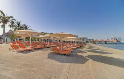 a row of chairs and umbrellas on a beach at One bedroom appartment Palm Jumeirah in Dubai