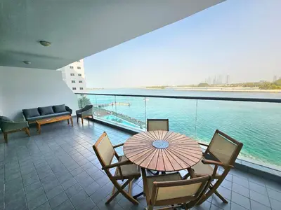 a balcony with a table and chairs and a view of the water at Beachfront-Huge Apt-in Palm-Private Beach in Dubai
