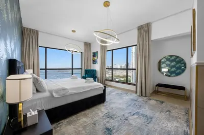 a bedroom with a large bed and large windows at Beachfront JBR Stunning Views, Pool & Gym in Dubai
