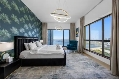 a bedroom with a bed and a chair and windows at Beachfront JBR Stunning Views, Pool & Gym in Dubai