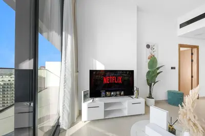 a living room with a flat screen tv on a cabinet at Luxurious JVC Getaway Infinity Pool & Gym in Dubai