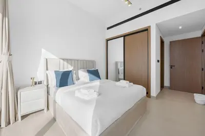 a bedroom with a large white bed with blue pillows at Luxurious JVC Getaway Infinity Pool & Gym in Dubai