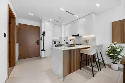 a kitchen with white cabinets and a bar with stools at Luxurious JVC Getaway Infinity Pool & Gym in Dubai