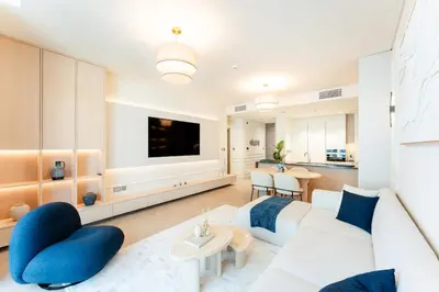 a living room with a white couch and blue chairs at Urban Haven Pool, Gym & Spectacular Views in Dubai