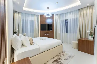 a bedroom with a large white bed and a television at Modern 2BR Prime Downtown Location in Dubai