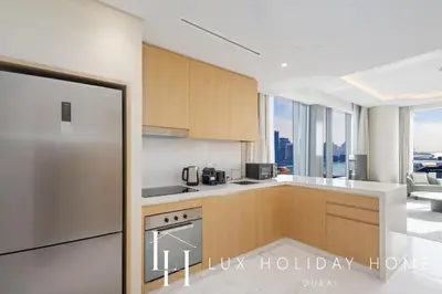 a kitchen with wooden cabinets and a stainless steel refrigerator at LUX Iconic Views at The Palm Tower Suite 8 in Dubai