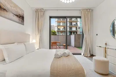 a white bedroom with a large bed and a balcony at FIRST CLASS 1BR Luxe Hideaway Escape in Dubai