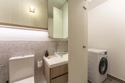 a bathroom with a sink and a washing machine at PVH - Kensington Waters - Lavish 1BR - Park Front in Dubai