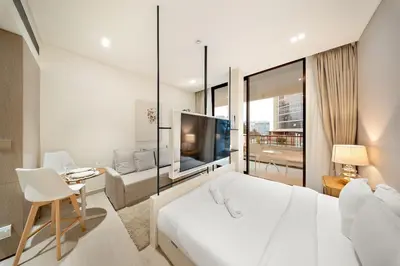 a white bedroom with a large bed and a tv at FIRST CLASS Studio Stylish Near Circle Mall in Dubai