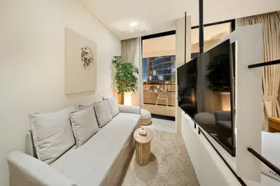 a living room with a white couch and a large tv at FIRST CLASS Studio Stylish Near Circle Mall in Dubai