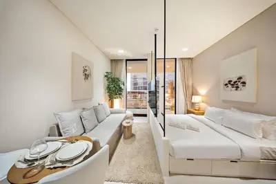 a white bedroom with a large bed and a couch at FIRST CLASS Studio Stylish Near Circle Mall in Dubai