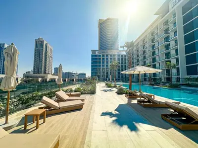 a pool with chairs and umbrellas next to a building at FIRST CLASS Studio Stylish Near Circle Mall in Dubai