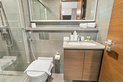 a bathroom with a toilet and a sink and a shower at FIRST CLASS 2BR Classy Getaway Near Downtown in Dubai