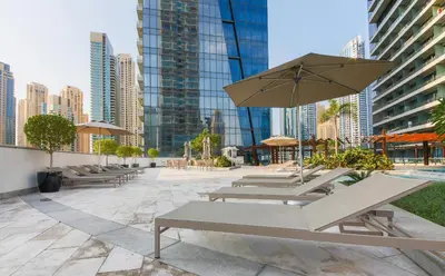 a group of tables and chairs with an umbrella at Silverene Tower A, Dubai Marina - Mint Stay in Dubai