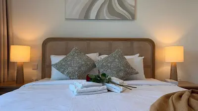 a bedroom with a bed with towels and two lamps at Serene 1BDR in Dubai Hills with Balcony in Dubai