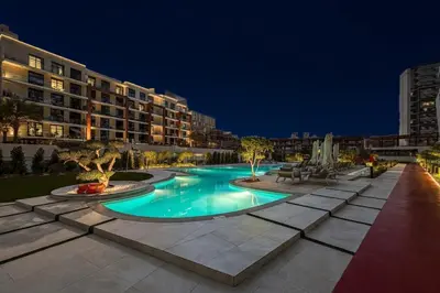 a large swimming pool in a city at night at Stylish 1BR with Pool & Gym Access in Dubai