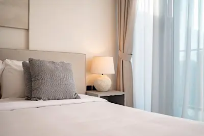 a bedroom with a bed with a lamp and a window at Stylish 1BR with Pool & Gym Access in Dubai