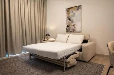 a bedroom with a bed and a couch and a chair at Stylish 1BR with Pool & Gym Access in Dubai