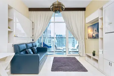 a living room with a blue couch and a large window at Burj Khalifa view cozy studio in Dubai