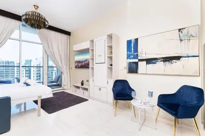 a bedroom with a bed and two blue chairs at Burj Khalifa view cozy studio in Dubai