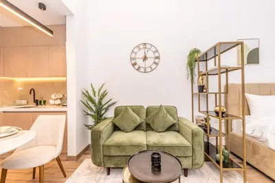 a living room with a green couch and a kitchen at Modern & Cozy JVC Studio Couple or Solo in Dubai