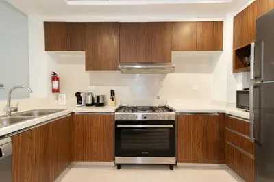 a kitchen with wooden cabinets and a stove at CitiHome - Spacious 2BR - Park Gate Residences in Dubai