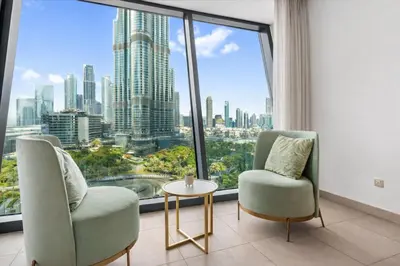 two chairs and a table in a room with a large window at Luxurious Burj Vista Apartment with Burj Khalifa view in Downtown Dubai in Dubai