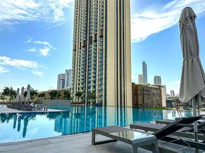 a large swimming pool with chairs and a large building at High Rise Building in Burj Vista with Burj Khalifa View in Dubai