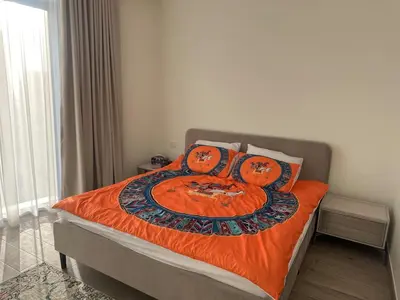 a bedroom with a bed with an orange blanket at have fun with your family and friends in our apt in Dubai