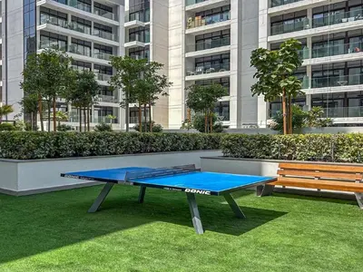 a ping pong table and a bench in front of a building at Stylish City Studio with Balcony View in Meydan in Dubai