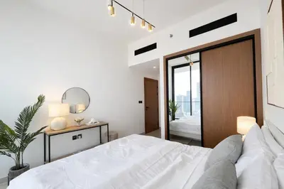 a white bedroom with a bed and a mirror at Luxury 2BR W Private Pool Binghattti Onyx in Dubai