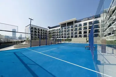 a tennis court in front of a building at Premium Studio W Pool & Gym Binghatti Aurora in Dubai