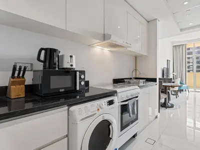 a white kitchen with a washer and dryer in it at Exquisite Lavish Studio in Ghalia JVC -16 in Dubai