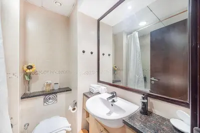 a bathroom with a sink and a toilet and a mirror at Daniels Studio with Lake View in JLT in Dubai