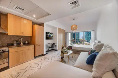 a kitchen and living room with a couch and a table at Daniels Studio with Lake View in JLT in Dubai