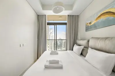 a bedroom with a large white bed with a large window at Daniels 2BR with Canal View at Aykon City in Dubai