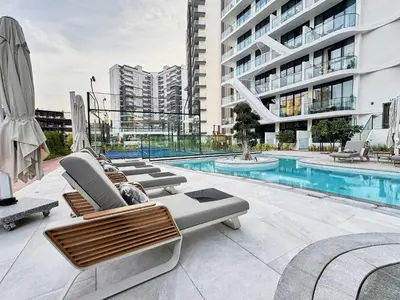 a swimming pool with lounge chairs next to a building at Frank Porter - Oxford Gardens in Dubai
