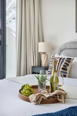 a tray with wine bottles and grapes on a bed at Frank Porter - Oxford Gardens in Dubai