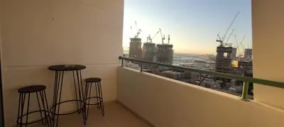 a balcony with two stools and a view of a city at Silk Valley - Luxury 1BR: Steps to Barasti Beach & Marina Walk in Dubai