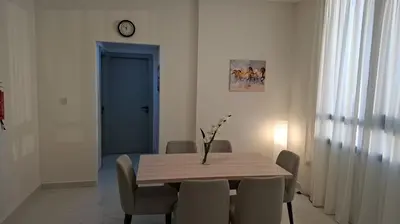 a dining room table with chairs and a clock on the wall at Equity Gate 217 in Dubai