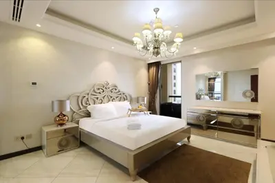 a bedroom with a large bed and a chandelier at Prime JBR 4B with Maid with Sea and Ain Dubai View in Dubai