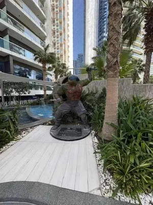 a man sitting on a statue next to a palm tree at Hollywood Glamour Epic Burj Views at DAMAC Towers by Paramount in Dubai