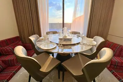 a dining room with a table and chairs and a window at Elegant 2BR Apartment with Huge Terrace, Dubai Land in Dubai