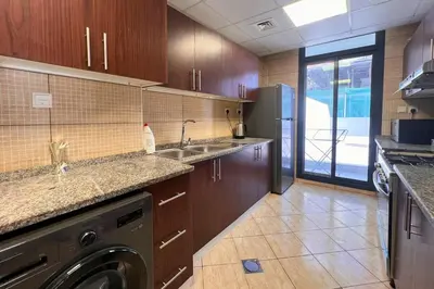 a kitchen with a sink and a dishwasher at Elegant 2BR Apartment with Huge Terrace, Dubai Land in Dubai