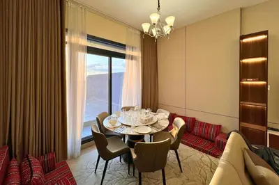 a dining room with a table and chairs and a window at Elegant 2BR Apartment with Huge Terrace, Dubai Land in Dubai