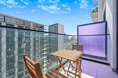 a balcony with a wooden table and two chairs at Binghatti House JVC - Parking, Balcony, Gym & Pool in Dubai