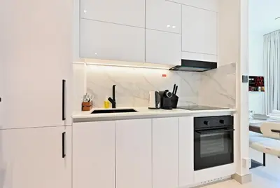 a white kitchen with white cabinets and a stove at Binghatti House JVC - Parking, Balcony, Gym & Pool in Dubai